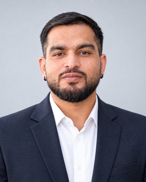 Portrait of Niranjan Kumar Agri in a dark navy suit and white shirt against a light grey background